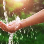 water pouring splash in hand and nature background with sunshine